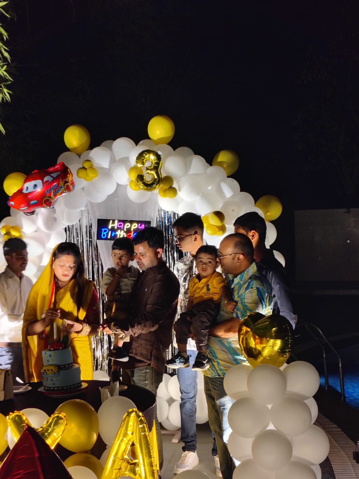 Family cutting birthday cake under a balloon arch at Nature's Lap Resort