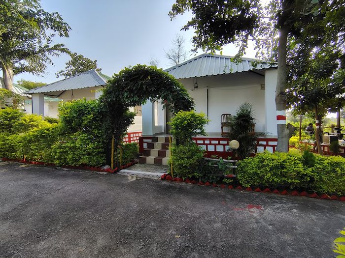 A guest cottage framed by a vine arch and clipped hedges in daylight