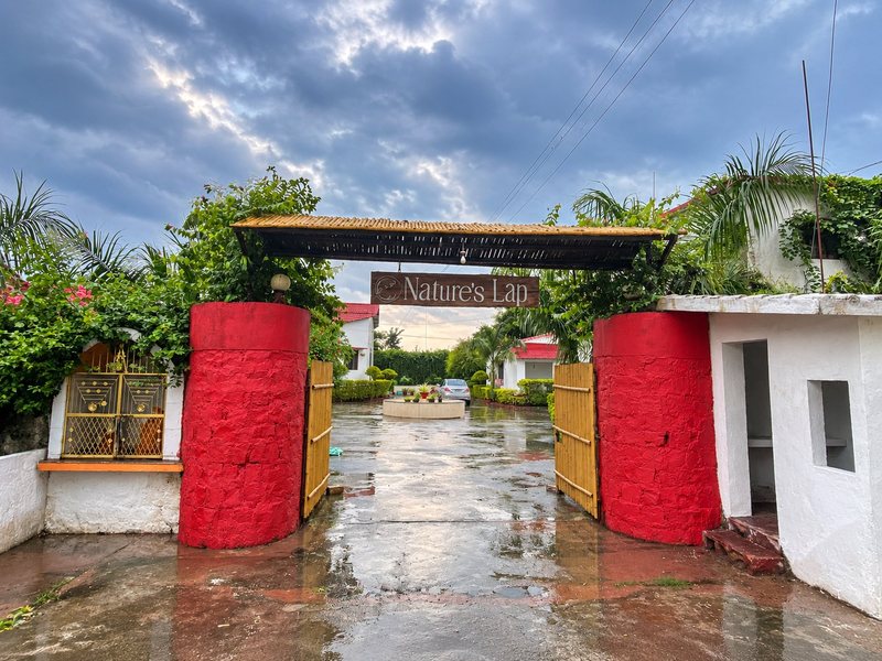 The resort's red-pillared entrance gate with the Nature's Lap sign, after evening rain
